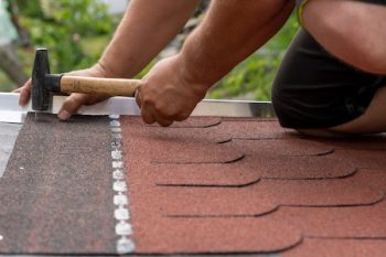 Worker Hands Installing Bitumen Roof Shingles